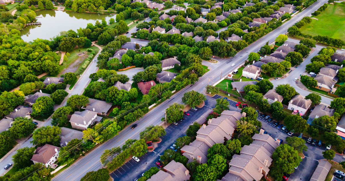 Aerial view of a Metro Denver neighborhood with homes, mature trees, and a lake