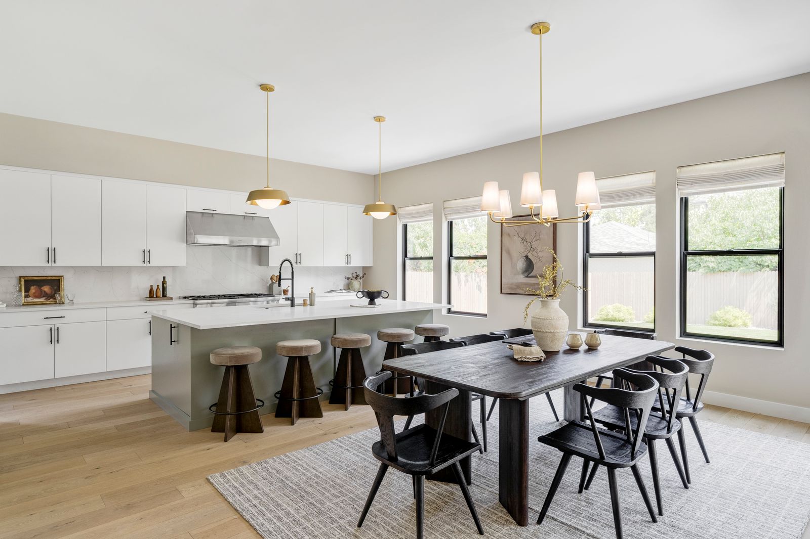 Bright kitchen and dining area with white cabinetry, a kitchen island, and a wooden dining table